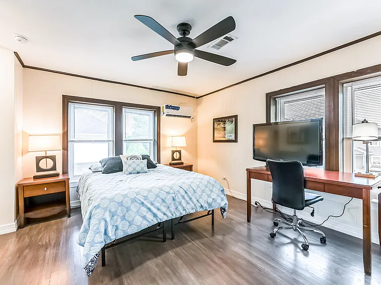 Upstairs room with minisplit AC, queen bed, hybrid mattress, night stand, full length mirror, and desk with chair and TV.