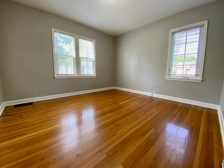 Bright and airy room with polished hardwood flooring and large windows, offering ample natural light and a cozy ambiance. Bright and airy room with polished hardwood flooring and large windows, offering ample natural light and a cozy ambiance.