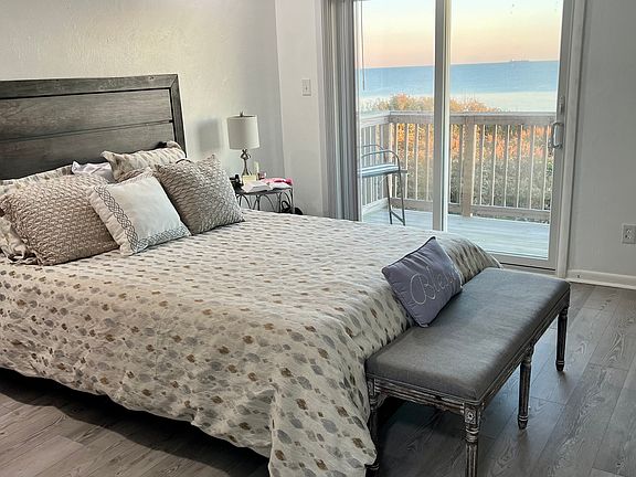 Waterfacing bedroom with bench. Ceiling fan, chair, night stand.