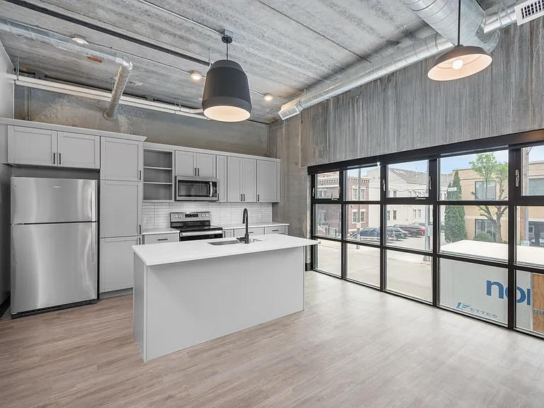 Chic urban kitchen with modern appliances, sleek cabinets, and expansive windows offering abundant natural light. Chic urban kitchen with modern appliances, sleek cabinets, and expansive windows offering abundant natural light.