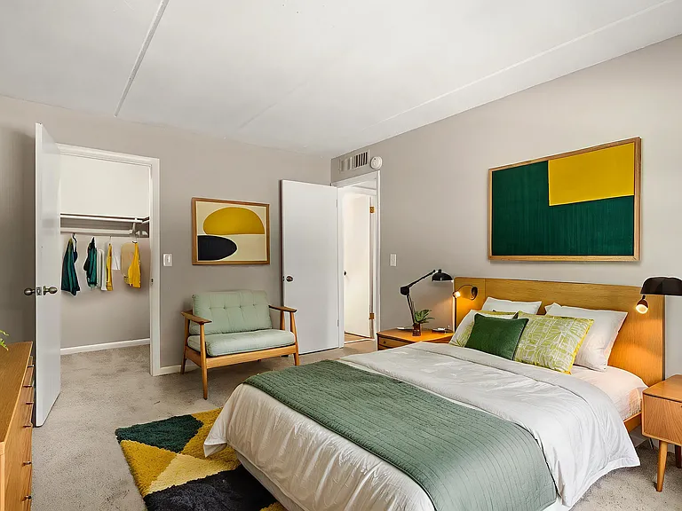 Bright and modern bedroom with a luxurious bed, stylish green and yellow accents, and a spacious closet, perfect for relaxation and comfort.
