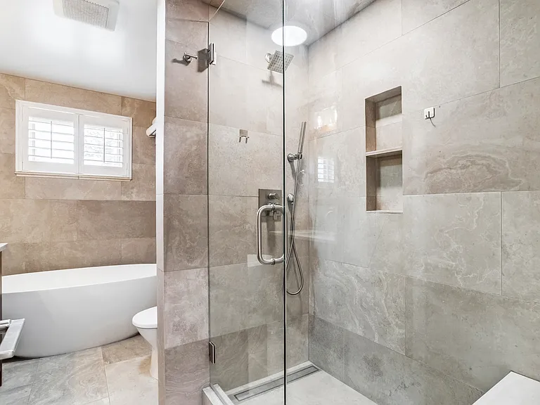 Floor to ceiling limestone, stand alone luxury bathtub and walk in shower