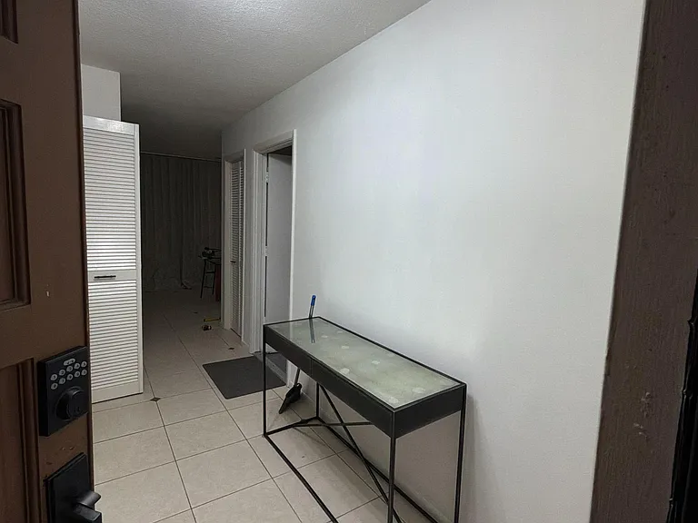 Tile-floored entry hallway with overhead light, convenient console table, and access to nearby rooms and storage.