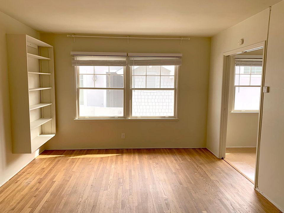 Living room with beautiful original oak hardwood floors, built in shelves and kitchen to the right