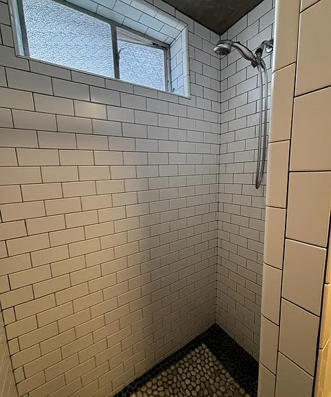 Shower with subway tiles and stone floor.