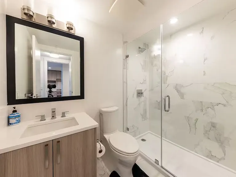 Step into a sleek and stylish primary bathroom designed for both comfort and functionality. A spacious stand-up shower with elegant glass doors
