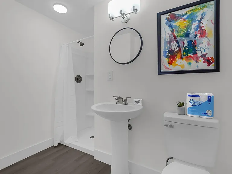 Personal clean full bath with a tub/shower combo, pedestal sink, and updated fixtures, plus wall art and durable flooring.