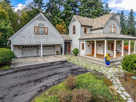 The home has an inviting wide columned front porch overlooking the luxuriant front lawn.  The covered portico (center of photo) leads from the utility room to the garage and upstairs ADU. The garage is massive, with parking for 3+ cars, as well as a workshop area with sink.  The windows above the garage are in the front of the ADU, which spans the entire length and breadth of the garage.