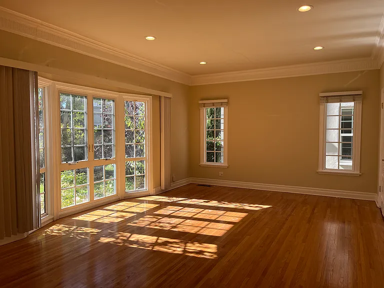 ELEGANT LIVING ROOM WITH LARGE BAY WINDOWS AND 2 ADDITIONAL WINDOWS OVERLOOK BEAUTIFUL GARDEN ROSES