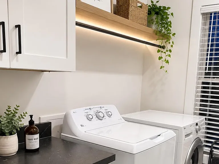 Dedicated laundry nook with washer/dryer, upper cabinetry, and a countertop area for sorting and folding.