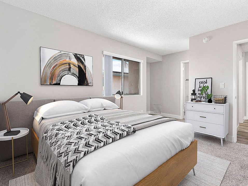 Carpeted bedroom with private bathroom and large exterior windows.