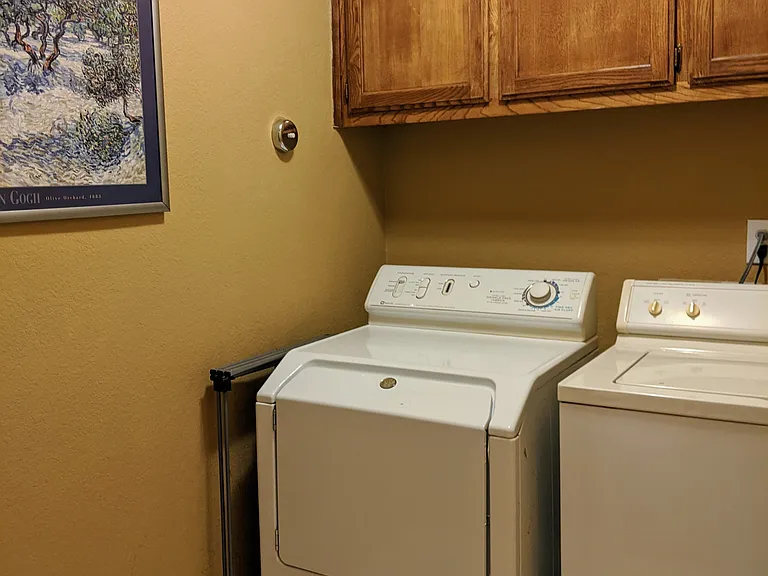 Laundry room equipped with full-size washer and dryer, drying rack and drying line, storage, vacuum, ironing board and iron