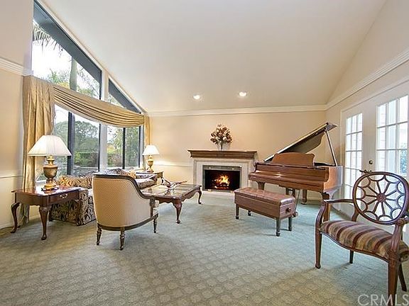Bright and open formal living room with french doors and fireplace surrounded by stone and a custom wood mantle