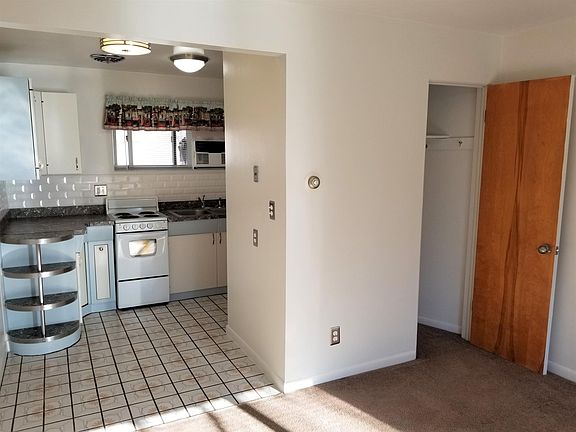 View from living room into kitchen, dining nook. Coat/storage closet in living room.