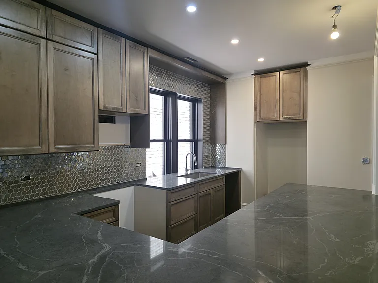 Kitchen with rich toned cabinets, quartz countertops and backsplash! (Appliances coming)