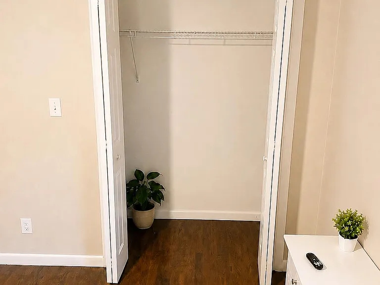 Bedroom features a dedicated closet with double doors and a full-length hanging shelf, plus durable wood-style flooring.