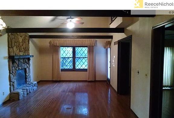 Living/Dining room with fireplace, wood floors, vaulted ceiling and access to the rear patio.