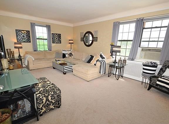 The bright and sunny, corner living room, with Southern and Eastern exposures, has covered hardwood 
