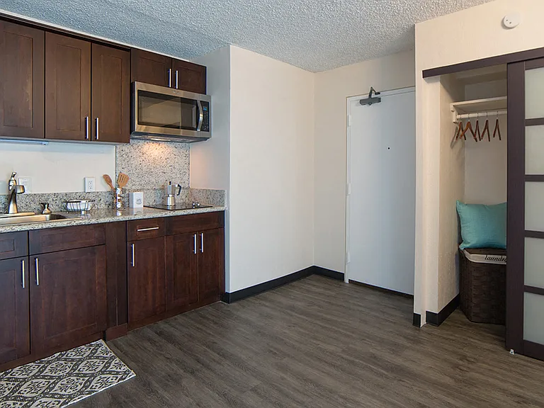 Waikiki Walina Apartments entry way with closet storage and kitchen area with appliances, cabinets, and counters