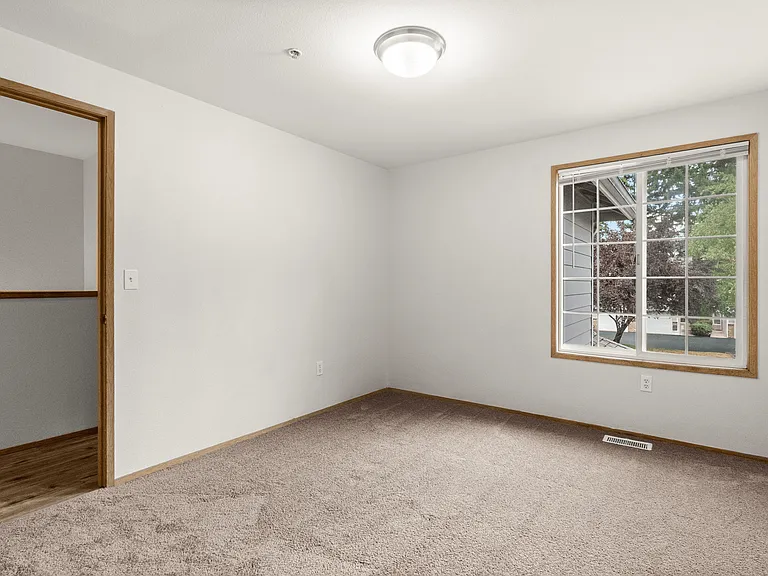 Bright bedroom featuring soft carpeting and a large window with peaceful outdoor views. Bright bedroom featuring soft carpeting and a large window with peaceful outdoor views.