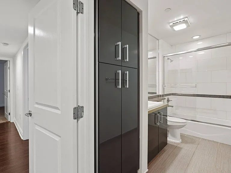 Bathroom with Full-Size Bathtub with Glass Door and Cabinet Storage