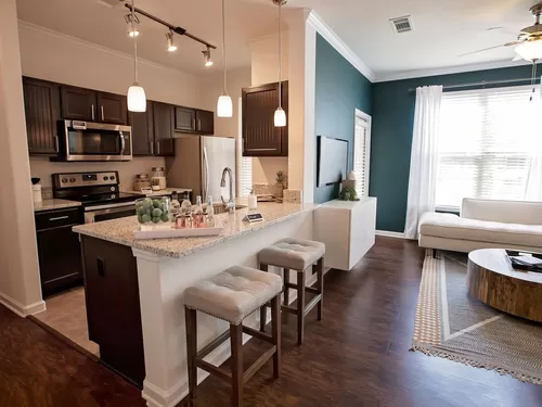 Kitchen with espresso cabinetry, granite countertops, stainless steel appliances, and tile flooring - Avalon Frisco at Main