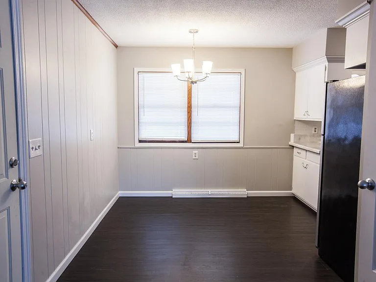 Dining room. Walls painted greige with dark vinyl plank flooring.
