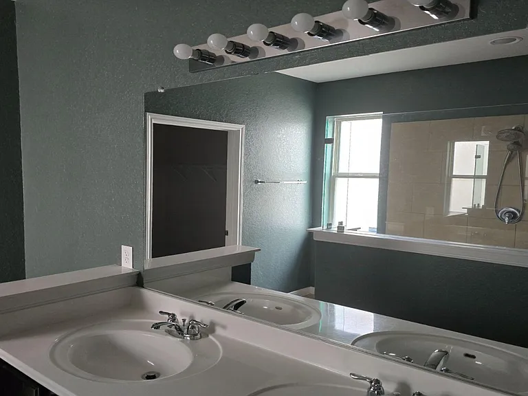 Full bathroom with wide vanity, large mirror, and a tub/shower with tile surround and a window for ventilation.