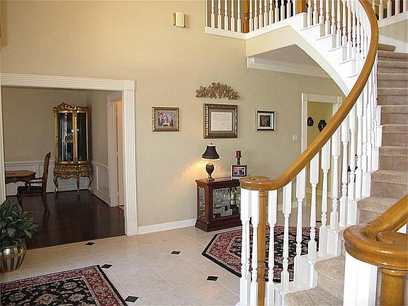 Breathtaking foyer offers winding staircase, leaded glass door, soaring ceilings, & tile flooring.