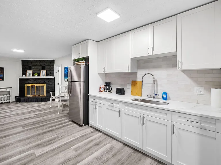 Updated kitchen with white shaker cabinetry, ample counter space, and stainless refrigerator, open to the main living area.