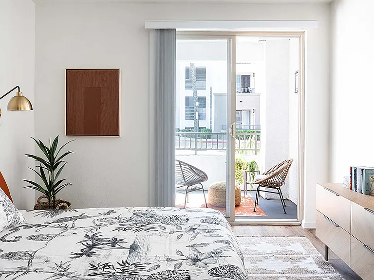 Spacious apartment bedroom with wood-style flooring and balcony access.