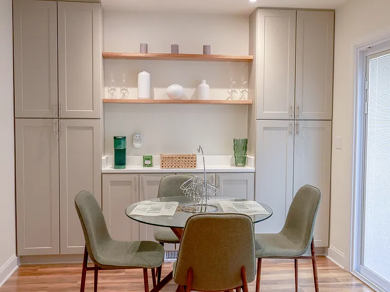 Modern dining space featuring floor-to-ceiling custom cabinetry, floating wood shelves, recessed lighting, and sliding glass doors for natural light.