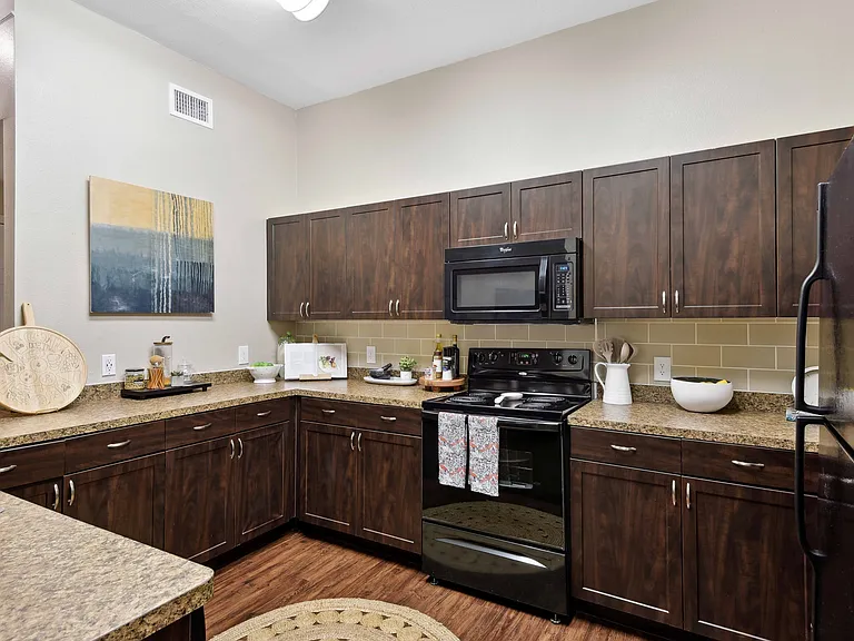 Kitchens feature black appliances, stylish tile backsplash, and Shaker-style cabinetry.