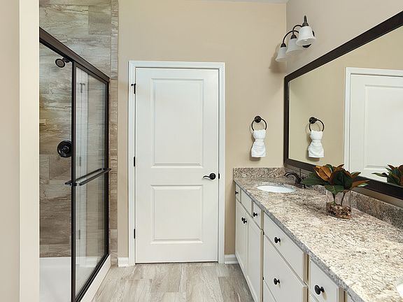 Owner s bath with walk-in tiled shower, large walk-in closet and cream cabinets and granite countert