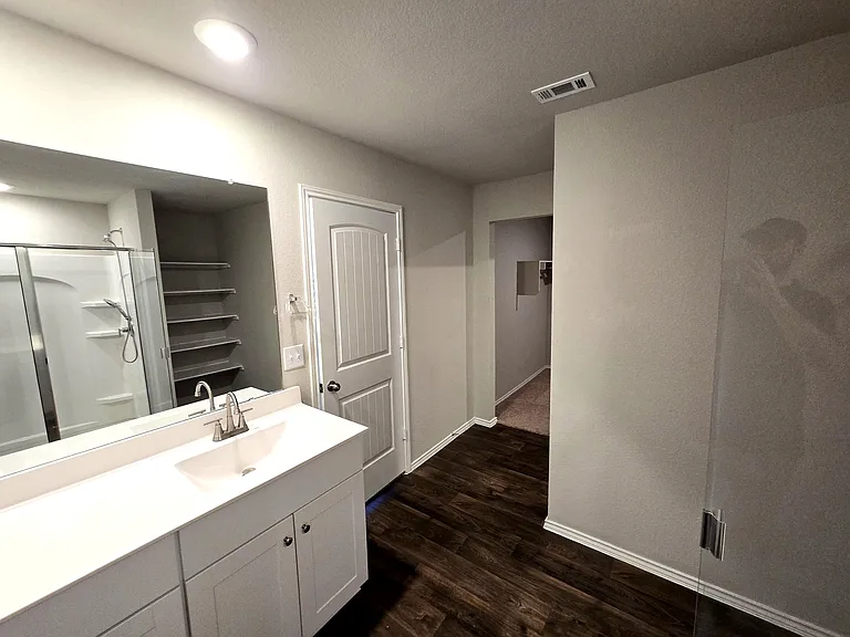 Clean and modern primary bathroom with ample space and storage with spacious walk-in closet providing excellent storage capacity.
