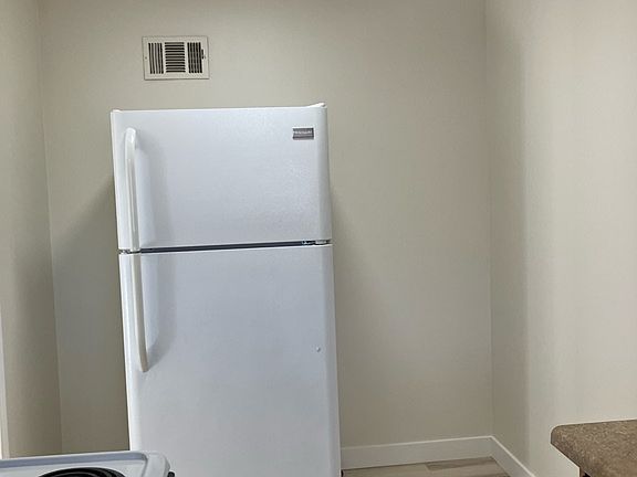 Kitchen has space for small table and chairs next to refrigerator.