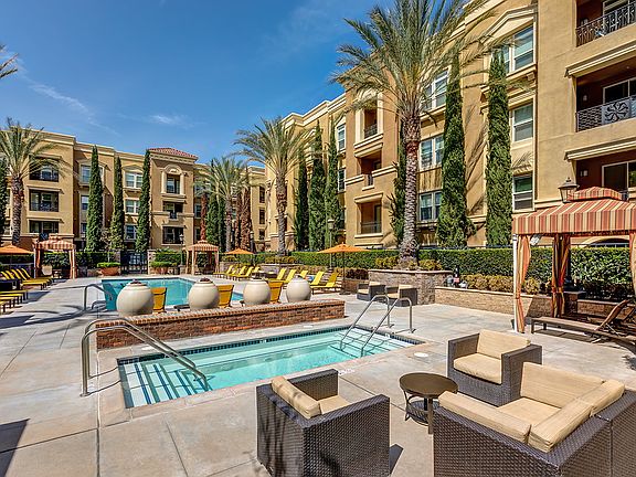 Swimming pool and spa surrounded by lounge chairs and cabanas.