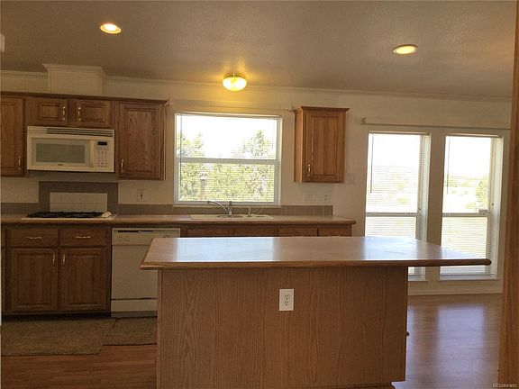Kitchen includes dishwasher, microwave, cook top, and oven appliances. Center island and lots of cabinets.