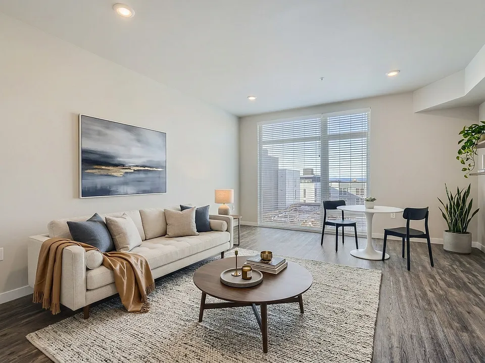 Open living layout at 306 Queen Anne featuring wood-style flooring, natural window light, and room for a dining table.