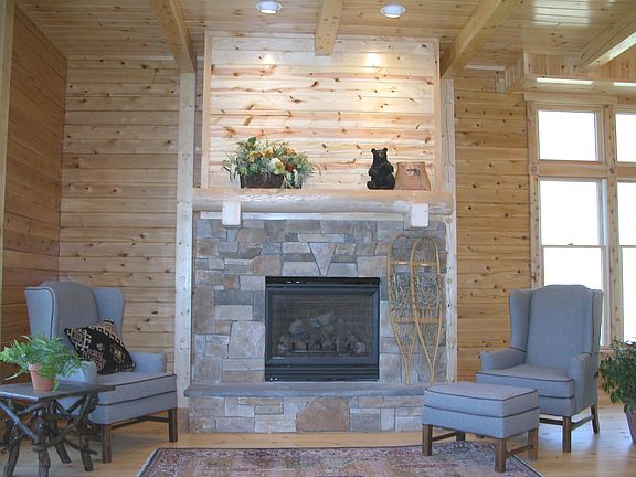 Top-grade gas fireplace is surrounded by cultured stone, log mantel