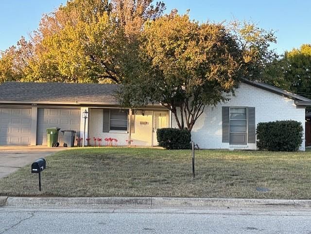 Ranch-style house featuring a front yard, brick siding, and an attached garage