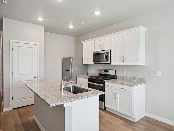 The kitchen has stainless steel appliances and plank flooring.