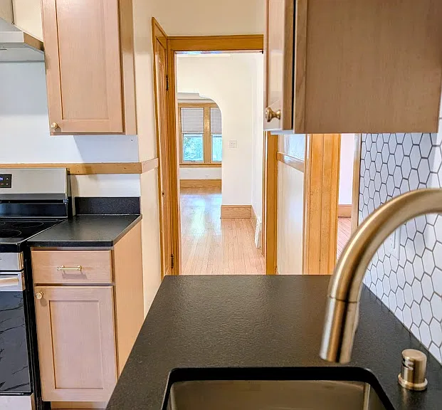 Kitchen leads into the living area straight ahead with bathroom and bedrooms to the right. Kitchen includes broom closet and pantry