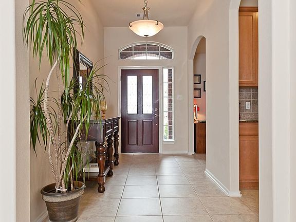 Entry way has ceramic tile flooring, leaded glass door, decorative archway to dining and kitchen, and an upgraded chandelier.