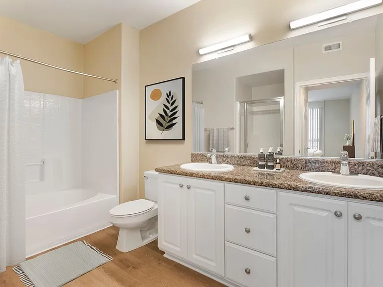 Renovated Package I bath with beige speckled granite countertop, white cabinetry, and hard surface flooring