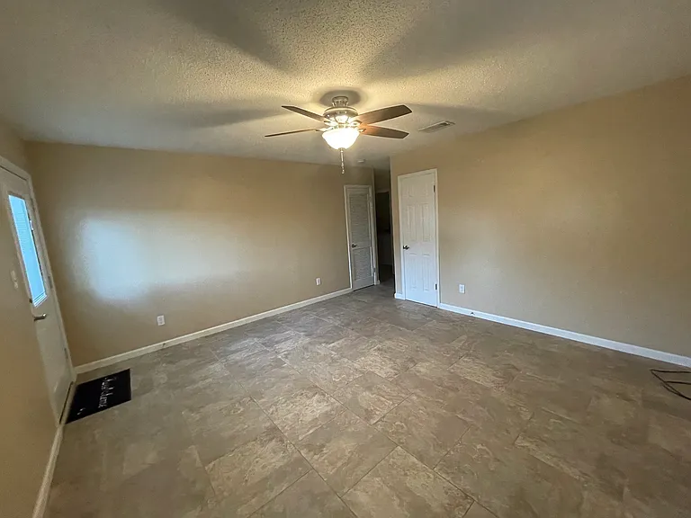 Living room with coat closet and air conditioner closet (louvered door). You can see the hallway to the kitchen and bedrooms.l