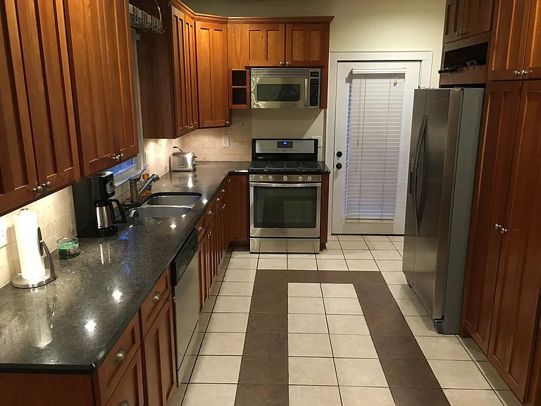 Kitchen with back door ahead, second bathroom and laundry past the fridge to the right.