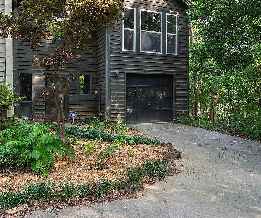 Outside, house is attached to townhome on the left, woods on right side of house