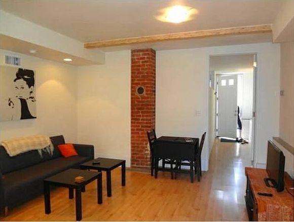 Living room featuring high ceilings, wooden beam, brick fireplace (non-working), bamboo flooring. Note: furniture is not included.