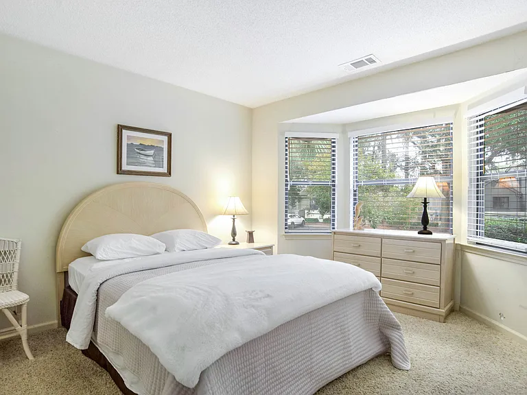 A bright and airy guest bedroom with a large bay window and cozy furnishings_ideal for family or friends. Thoughtfully designed for comfort and relaxation.
